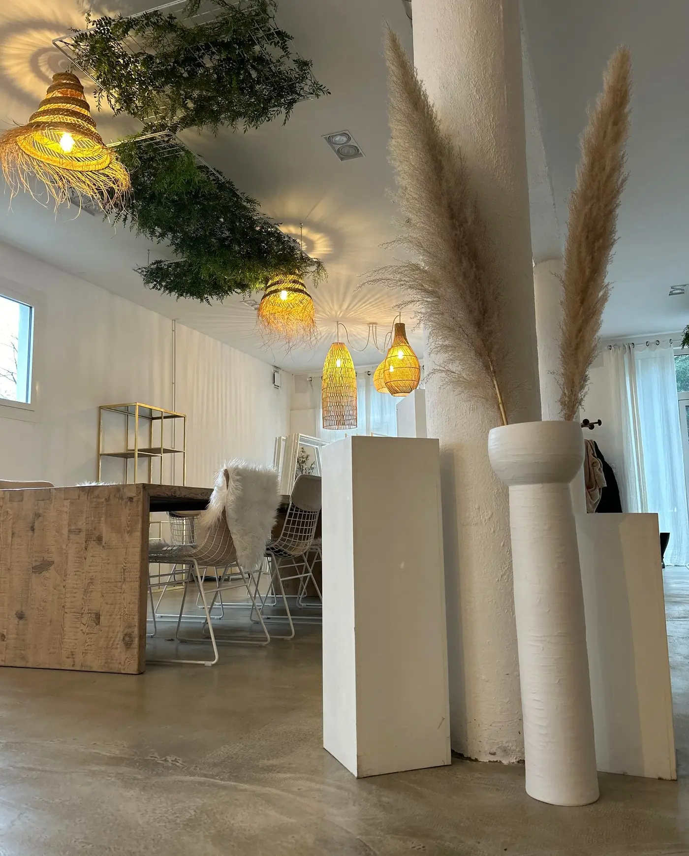 Intérieur lumineux du Kinfolk Studio à Tarnos : colonnes blanches, plantes suspendues et grand volume ouvert